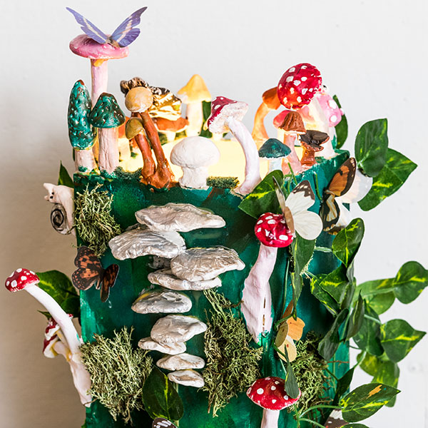 A sculpture of a log with colorful mushrooms, butterflies and leaves.